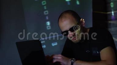 一个戴太阳镜的黑客在黑暗的房间里使用程序代码